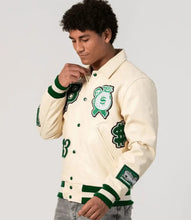 Load image into Gallery viewer, Person wearing a cream varsity jacket with green accents and designs on a plain background
